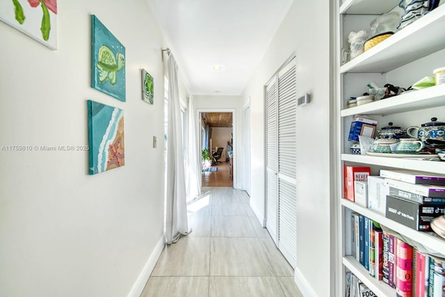 hall featuring tile patterned flooring and baseboards