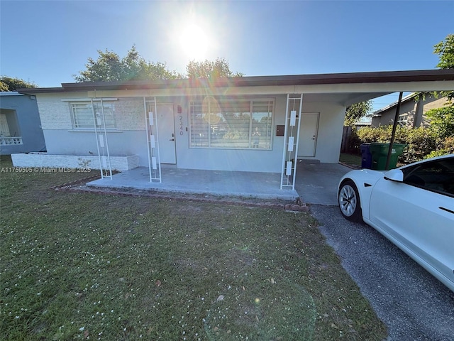 view of front of house with a carport, stucco siding, and a front yard