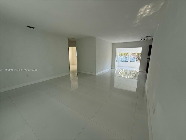 spare room featuring tile patterned flooring, visible vents, track lighting, and baseboards