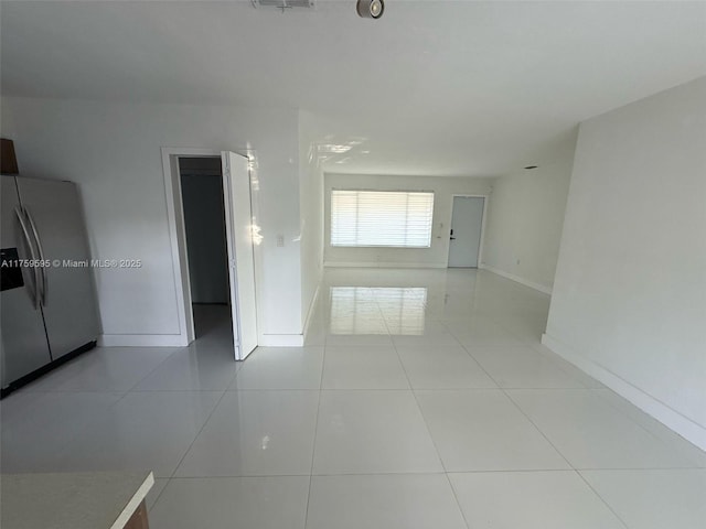 spare room featuring light tile patterned floors, visible vents, and baseboards