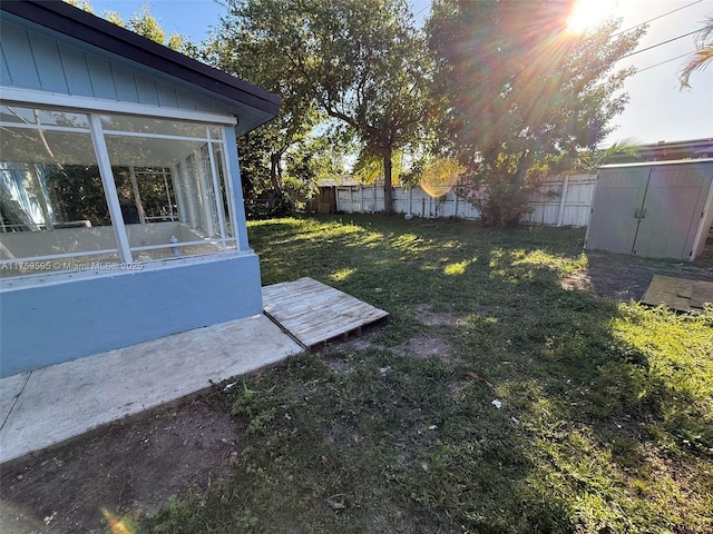 view of yard featuring a storage unit, fence, an outbuilding, and a sunroom