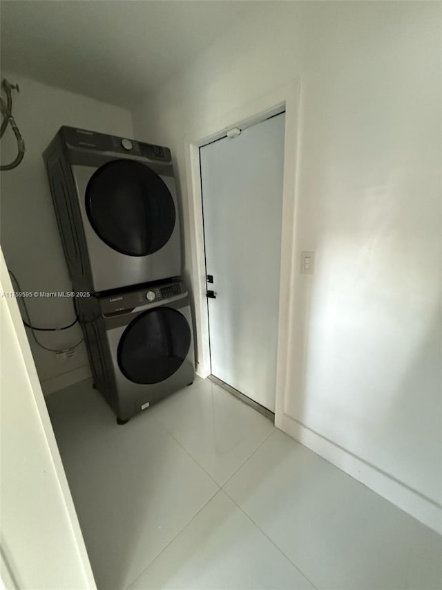 laundry room featuring tile patterned flooring, laundry area, and stacked washer / dryer