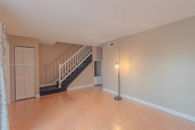 tiled spare room with stairway, baseboards, and visible vents