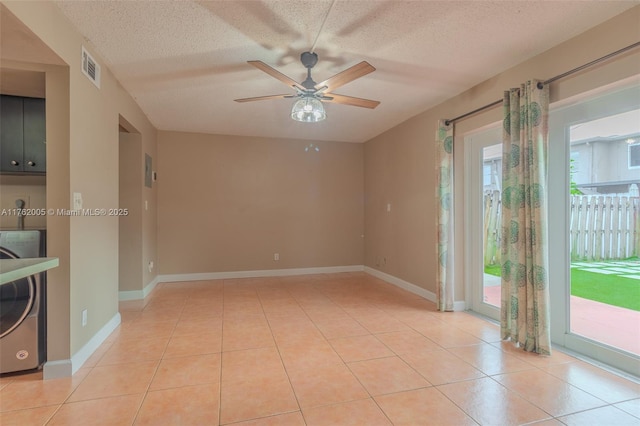 empty room featuring light tile patterned floors, visible vents, a textured ceiling, and washer / clothes dryer