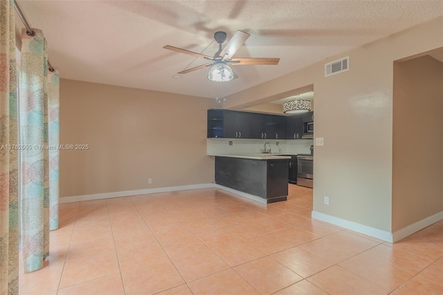 spare room featuring light tile patterned floors, a ceiling fan, visible vents, and a textured ceiling