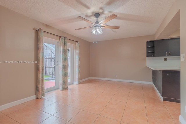 spare room with light tile patterned floors, baseboards, and a textured ceiling