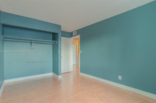 unfurnished bedroom with tile patterned floors, a closet, and a textured ceiling