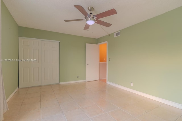 spare room featuring light tile patterned floors, baseboards, visible vents, and ceiling fan