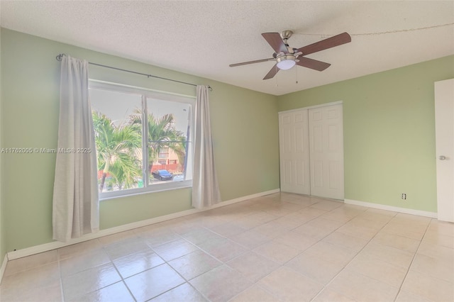 unfurnished bedroom with a ceiling fan, baseboards, a closet, a textured ceiling, and tile patterned floors