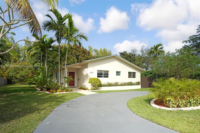 ranch-style house with stucco siding, concrete driveway, and a front yard