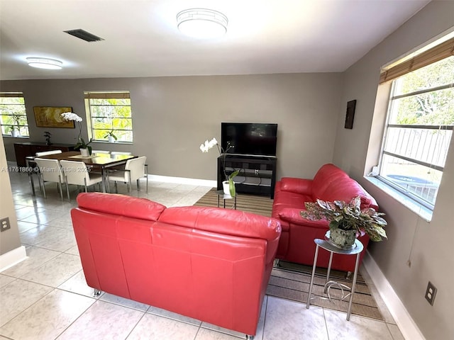 living room with a wealth of natural light, baseboards, and tile patterned flooring