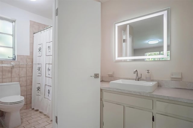 bathroom featuring a wealth of natural light, toilet, tile walls, and vanity