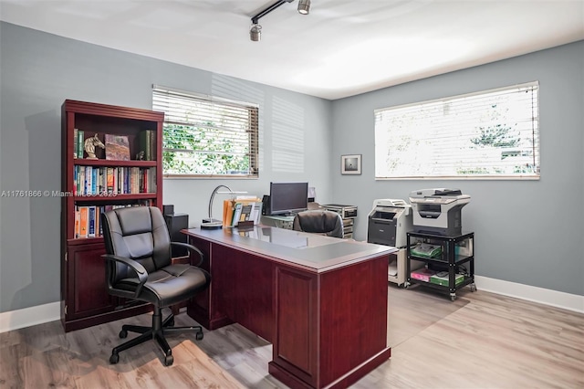 office featuring track lighting, light wood-style flooring, and baseboards