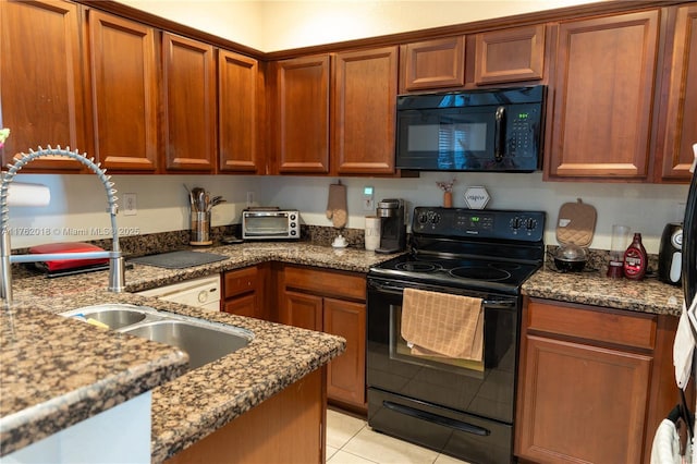 kitchen featuring dark stone countertops, light tile patterned floors, brown cabinetry, a sink, and black appliances