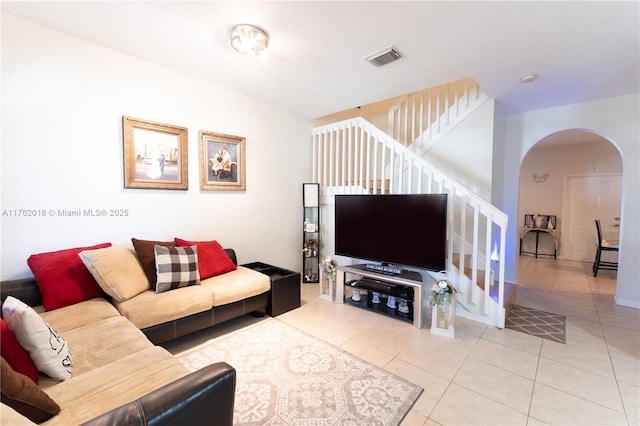 living area featuring stairs, arched walkways, visible vents, and tile patterned flooring