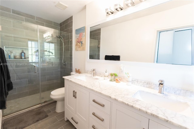 full bathroom with double vanity, toilet, a stall shower, and a sink