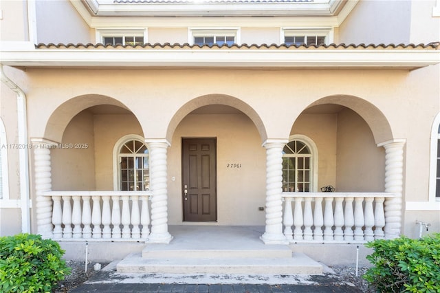 property entrance with stucco siding and a porch