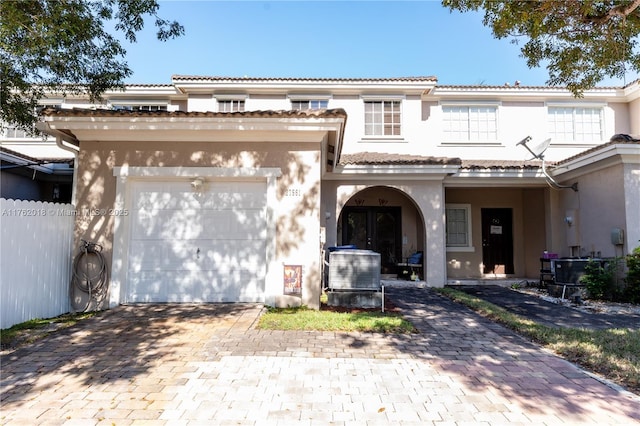 view of front of house featuring stucco siding, an attached garage, decorative driveway, and fence