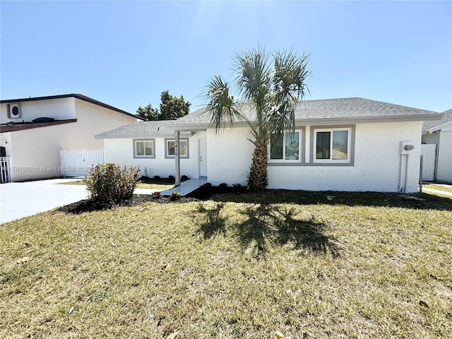 view of front of house featuring a shingled roof, a front lawn, fence, and stucco siding