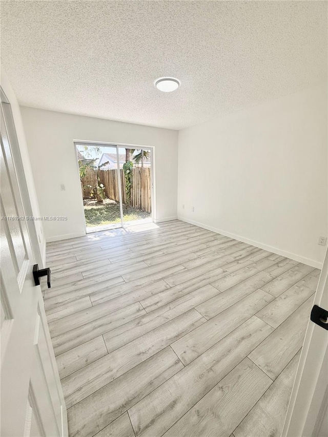 unfurnished room with baseboards, a textured ceiling, and wood finished floors