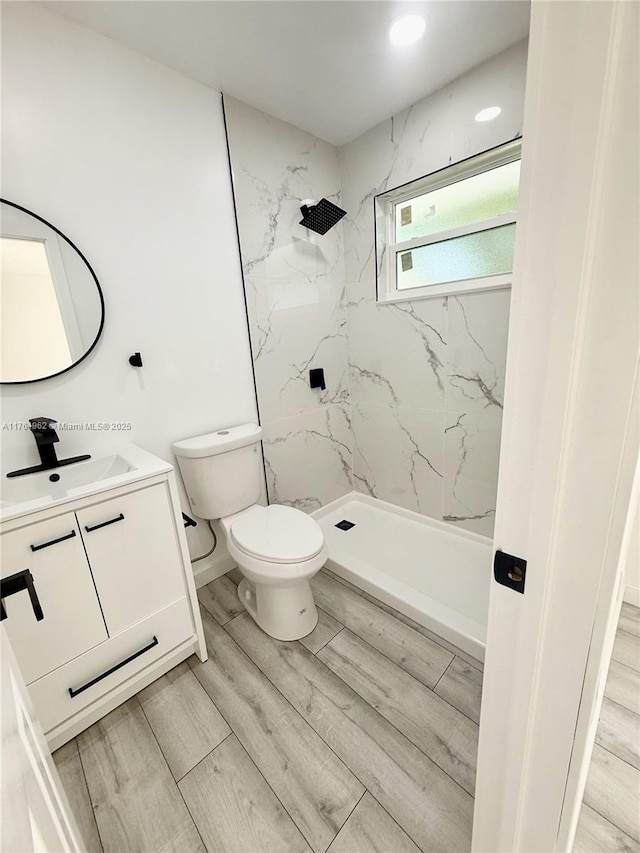 full bath featuring toilet, vanity, walk in shower, and wood finished floors