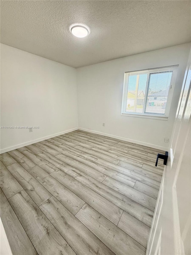 unfurnished room featuring wood finished floors, baseboards, and a textured ceiling