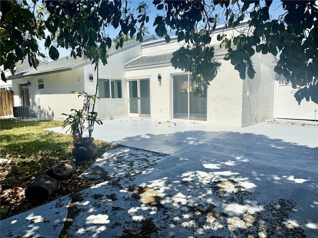 rear view of house featuring a patio, central air condition unit, fence, and stucco siding