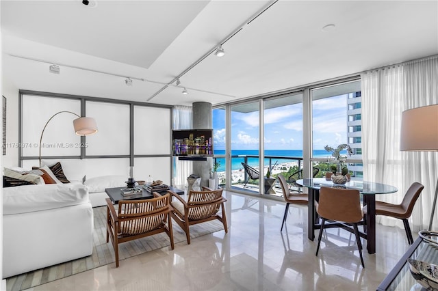 living room featuring track lighting, a wall of windows, and a water view