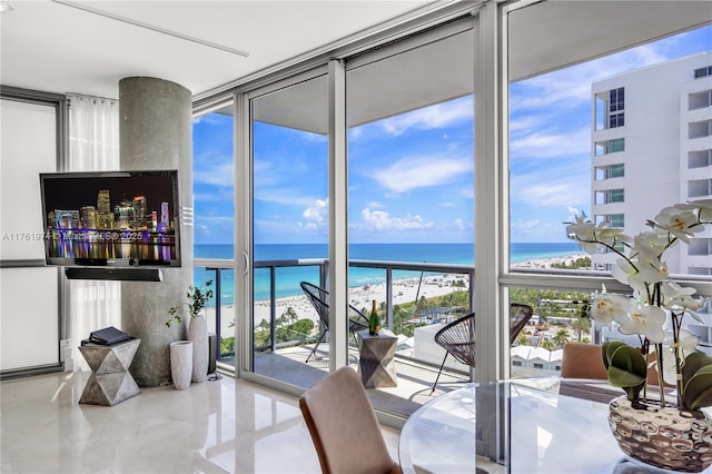 dining space with a wall of windows, a view of the beach, and a water view