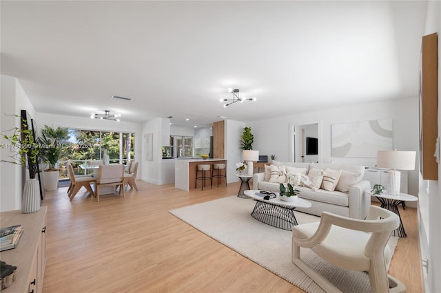 living room with a notable chandelier, visible vents, and light wood-type flooring