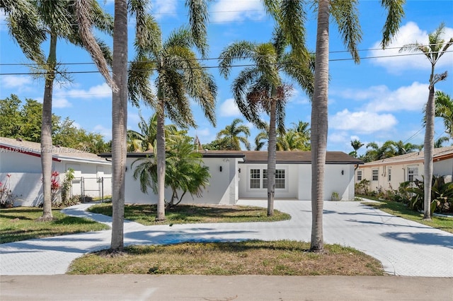 view of front of home with decorative driveway, fence, and stucco siding