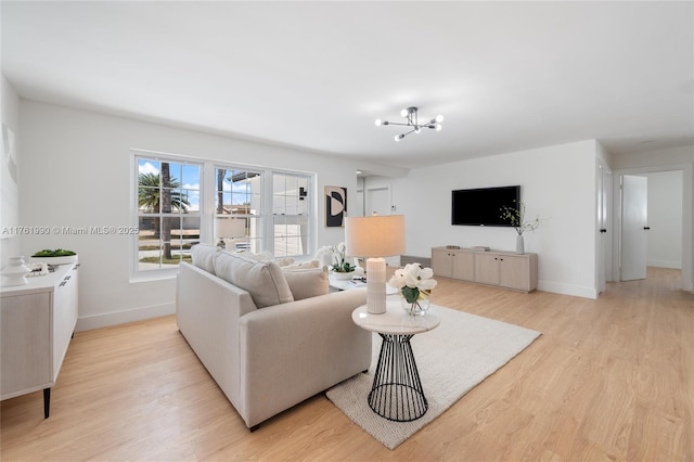 living area featuring an inviting chandelier, light wood-style floors, and baseboards