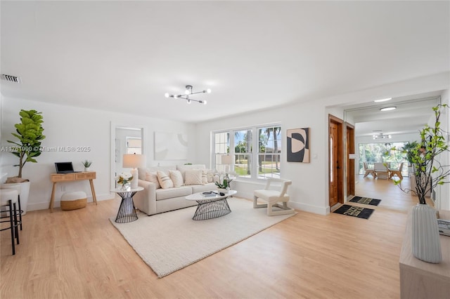 living room featuring light wood finished floors, visible vents, a healthy amount of sunlight, and baseboards