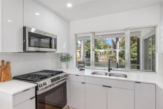 kitchen with a sink, light countertops, white cabinets, and stainless steel appliances