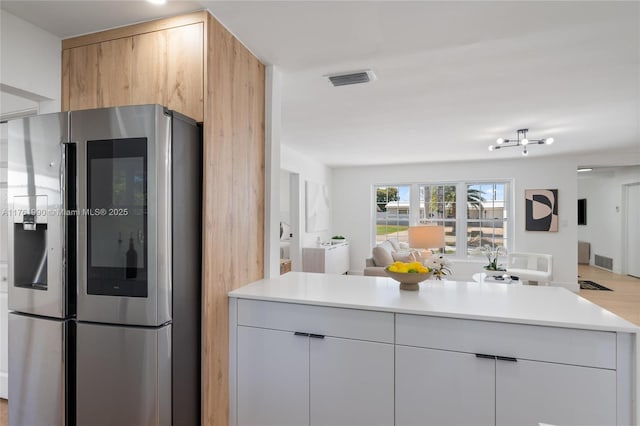 kitchen with light countertops, open floor plan, modern cabinets, and stainless steel refrigerator with ice dispenser