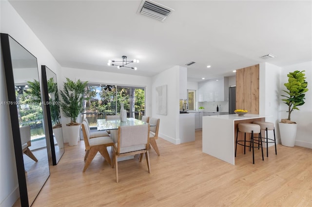 dining area with light wood-style flooring, baseboards, and visible vents