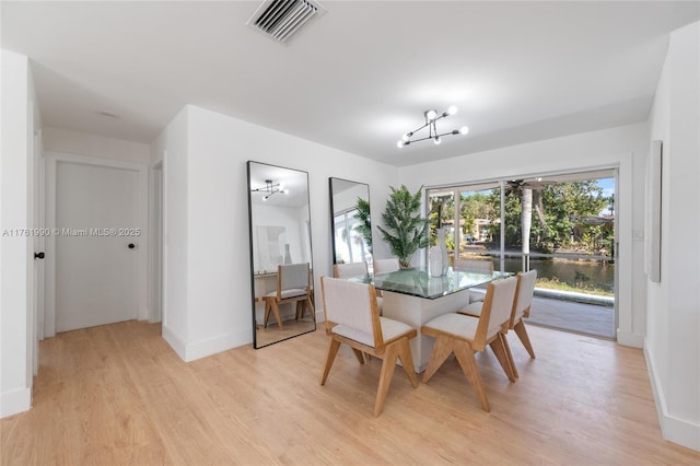 dining room with light wood-type flooring, visible vents, baseboards, and a chandelier