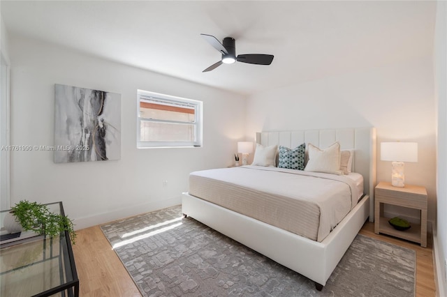 bedroom with a ceiling fan, wood finished floors, and baseboards