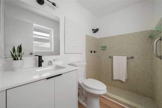 full bath featuring tiled shower, toilet, wood finished floors, and vanity