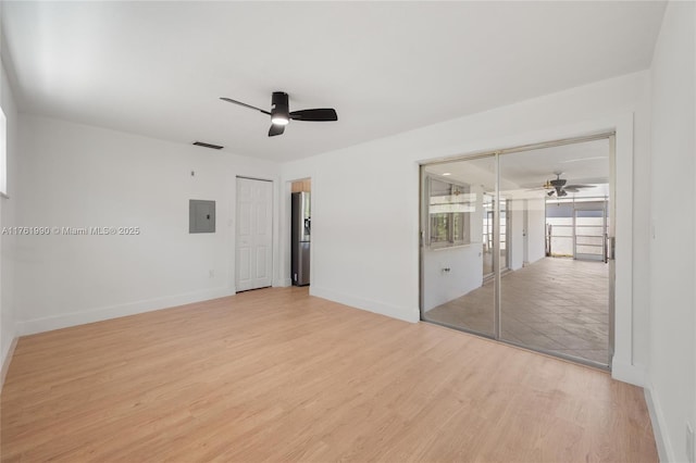 unfurnished bedroom featuring a ceiling fan, baseboards, light wood finished floors, electric panel, and stainless steel fridge with ice dispenser