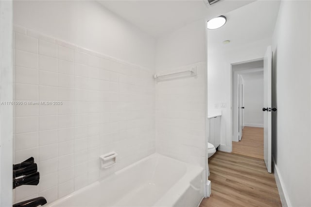 full bathroom with  shower combination, toilet, wood finished floors, and baseboards