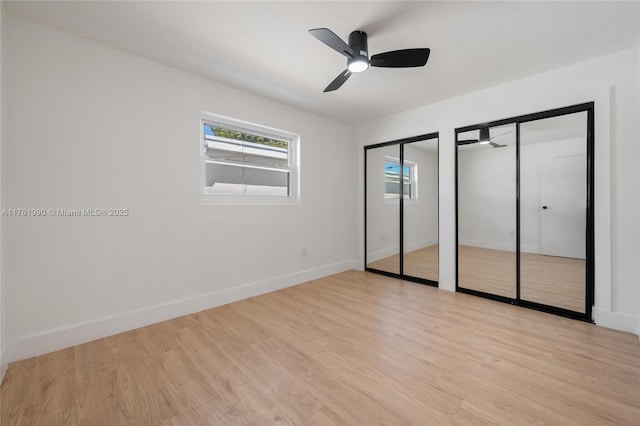 unfurnished bedroom featuring ceiling fan, light wood-style floors, multiple closets, and baseboards