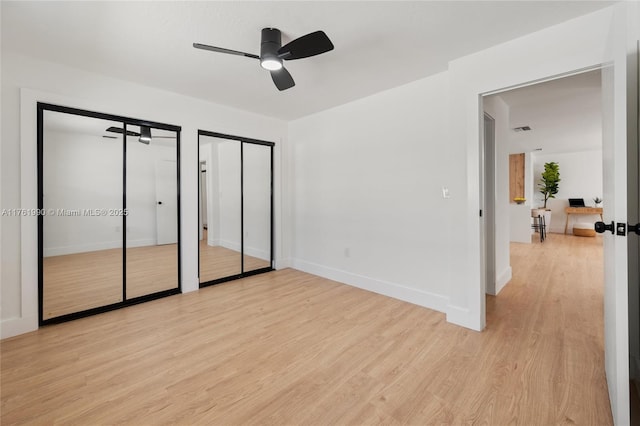 unfurnished bedroom featuring baseboards, two closets, light wood-style floors, and a ceiling fan