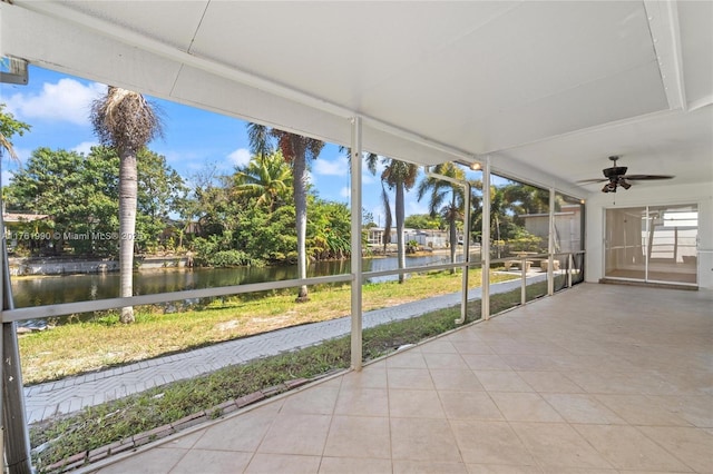 unfurnished sunroom featuring a ceiling fan and a water view