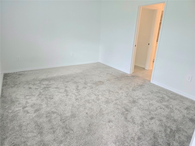 carpeted empty room featuring baseboards