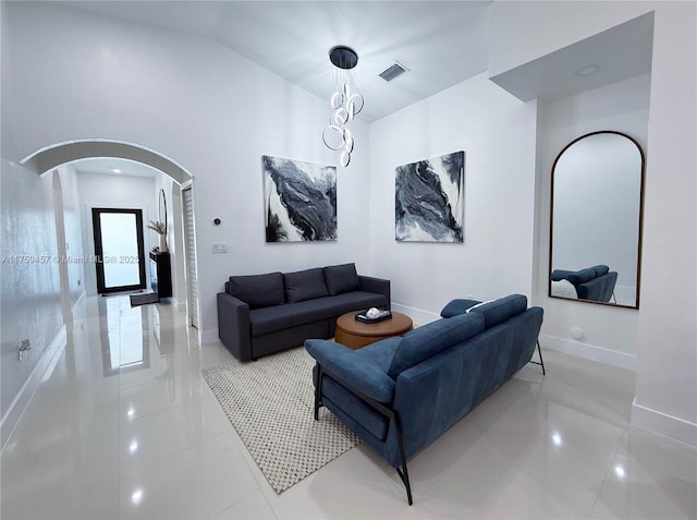 living room with high vaulted ceiling, arched walkways, visible vents, and baseboards