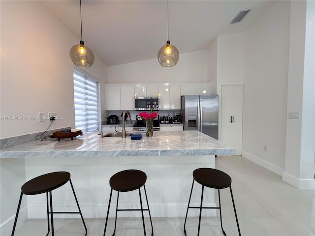 kitchen featuring appliances with stainless steel finishes, modern cabinets, a kitchen bar, and a peninsula