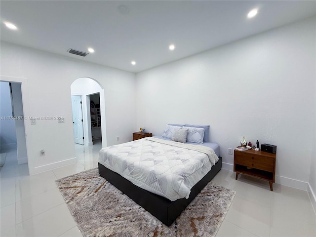 bedroom with visible vents, a walk in closet, light tile patterned floors, recessed lighting, and arched walkways