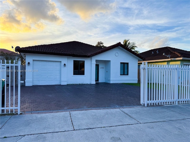 view of front of property featuring decorative driveway, an attached garage, fence, and stucco siding