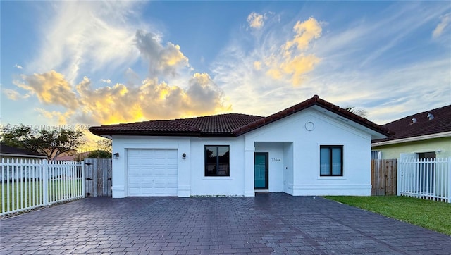 mediterranean / spanish house featuring a tile roof, fence, a garage, and stucco siding